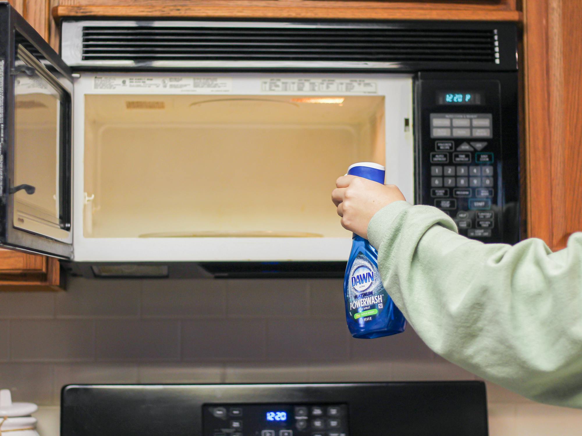 a person spraying dish soap into a microwave