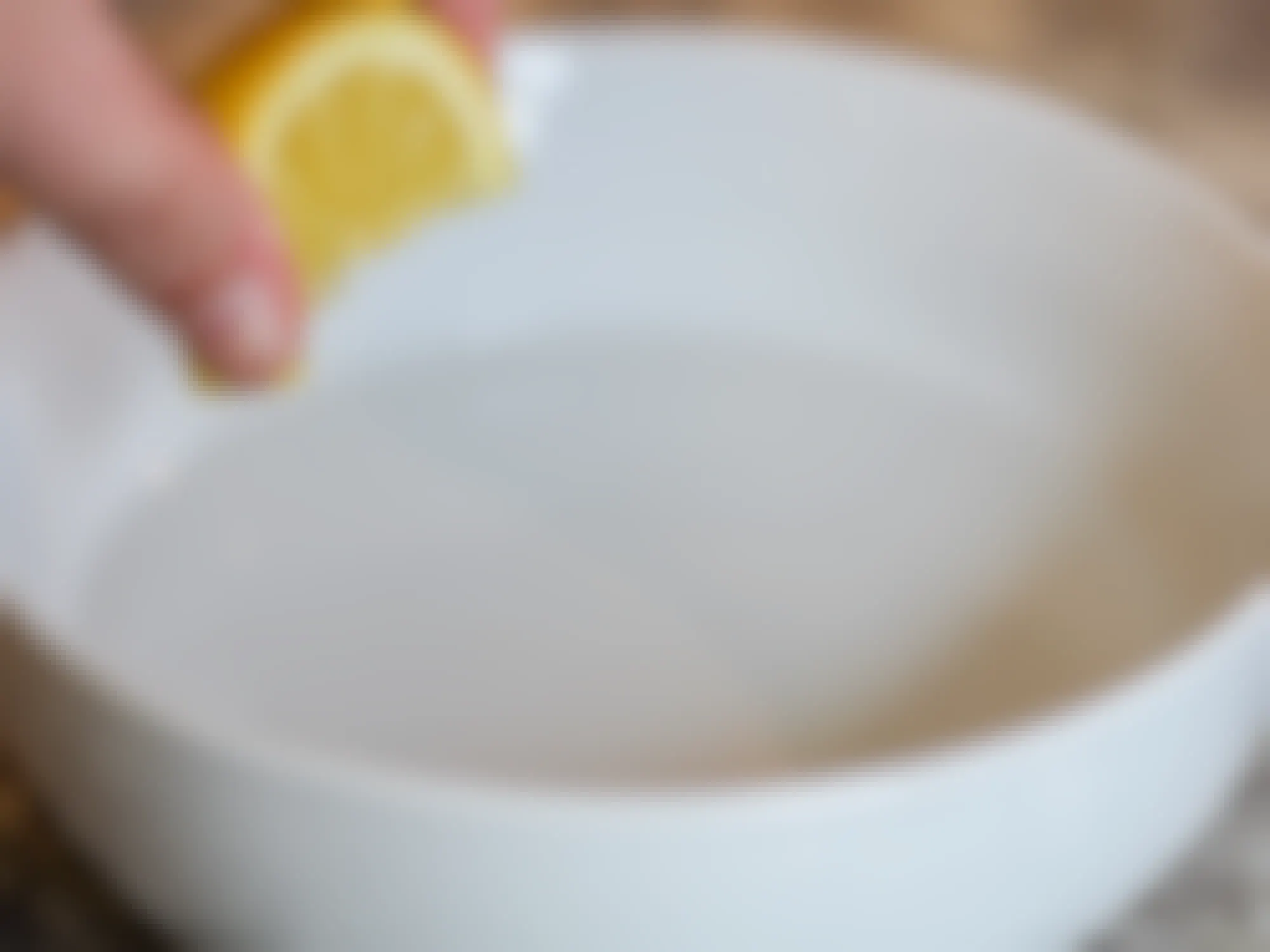 a person squeezing a lemon wedge into a bowl full of water