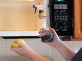 a person looking at a bottle of vinegar and a lemon