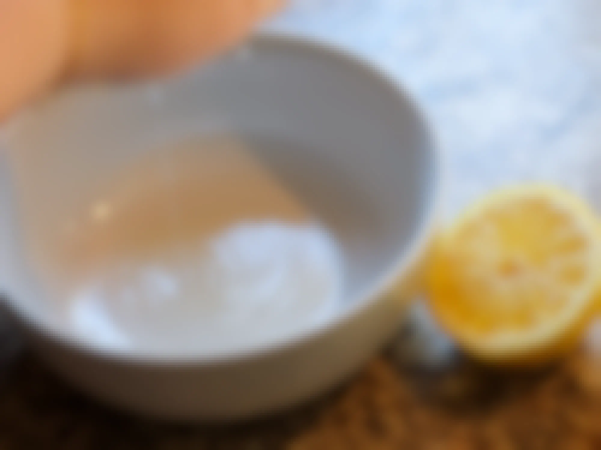 half of a lemon being squeezed into a white bowl before being placed into a microwave
