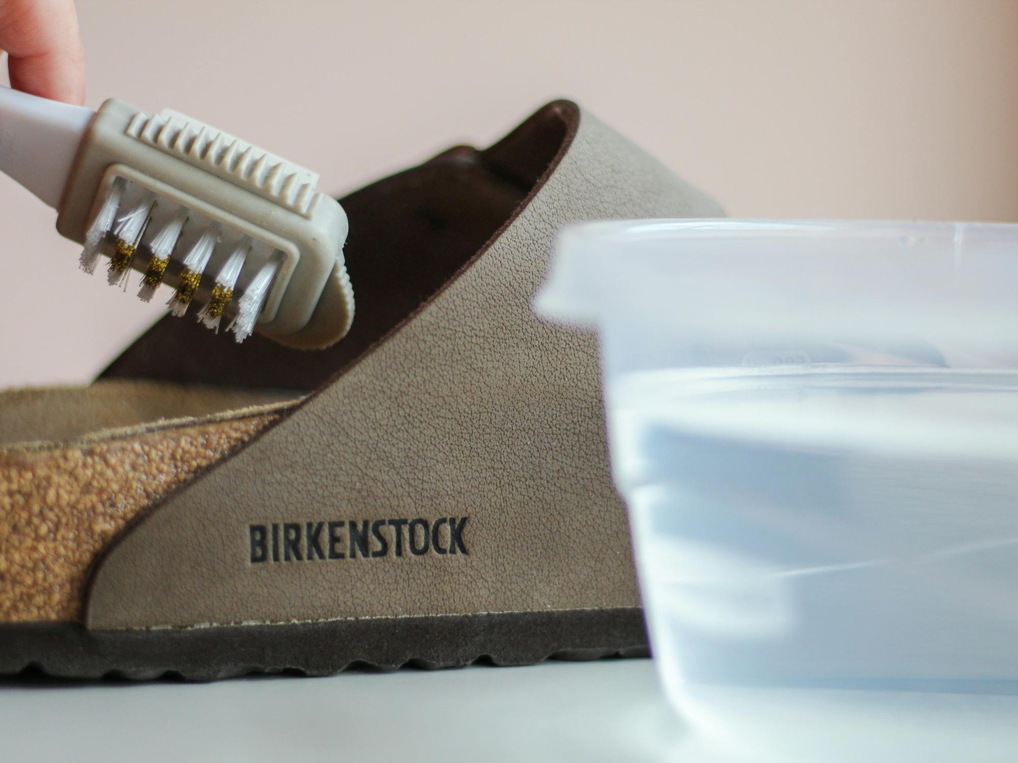 a person cleaning the footbed of Birkenstocks with a soft brush and water solution