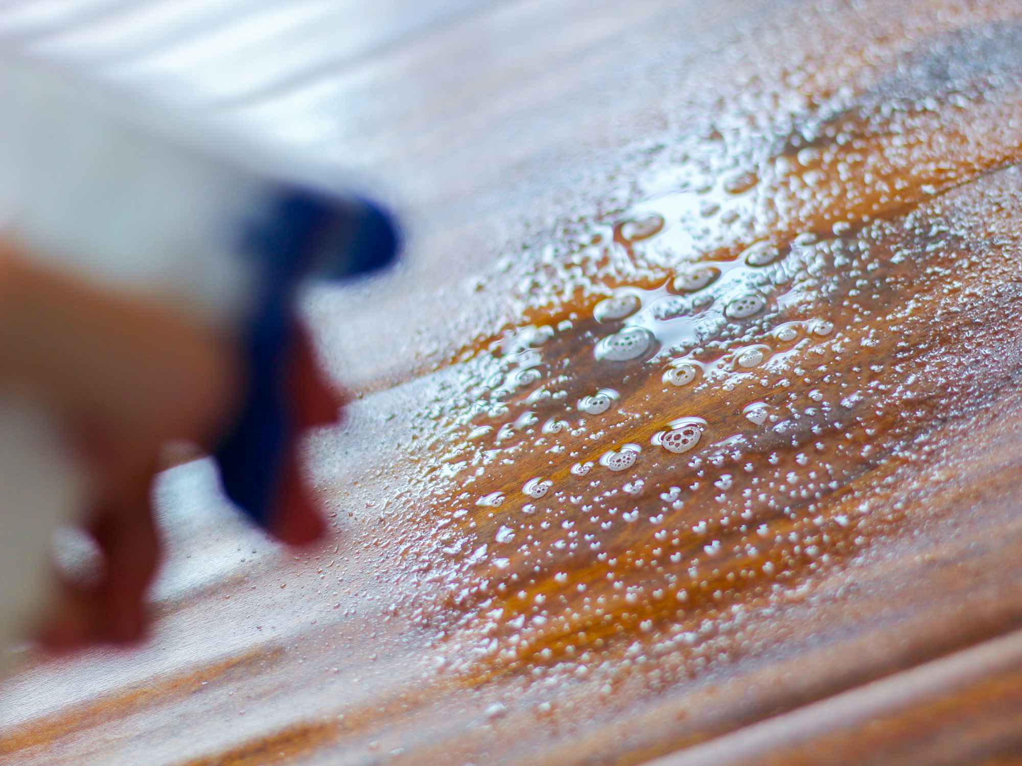 a person spraying cleaning solution on hardwood floors