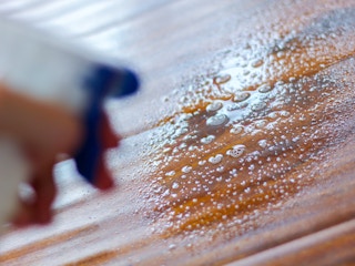 a person spraying cleaning solution on hardwood floors