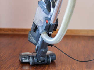 a person vacuuming up dirt and debris from hardwood floor