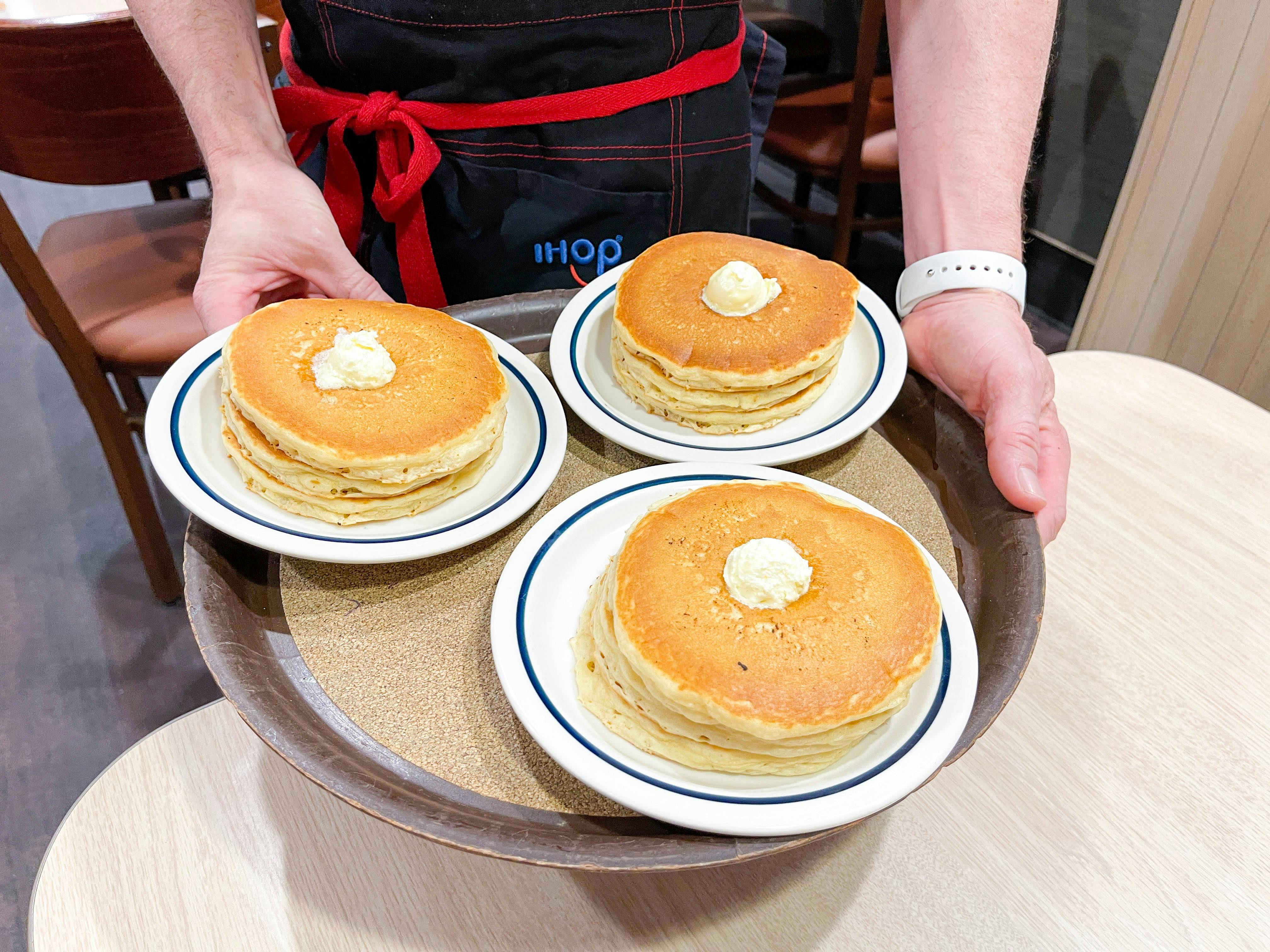 an ihop server with a tray of pancakes