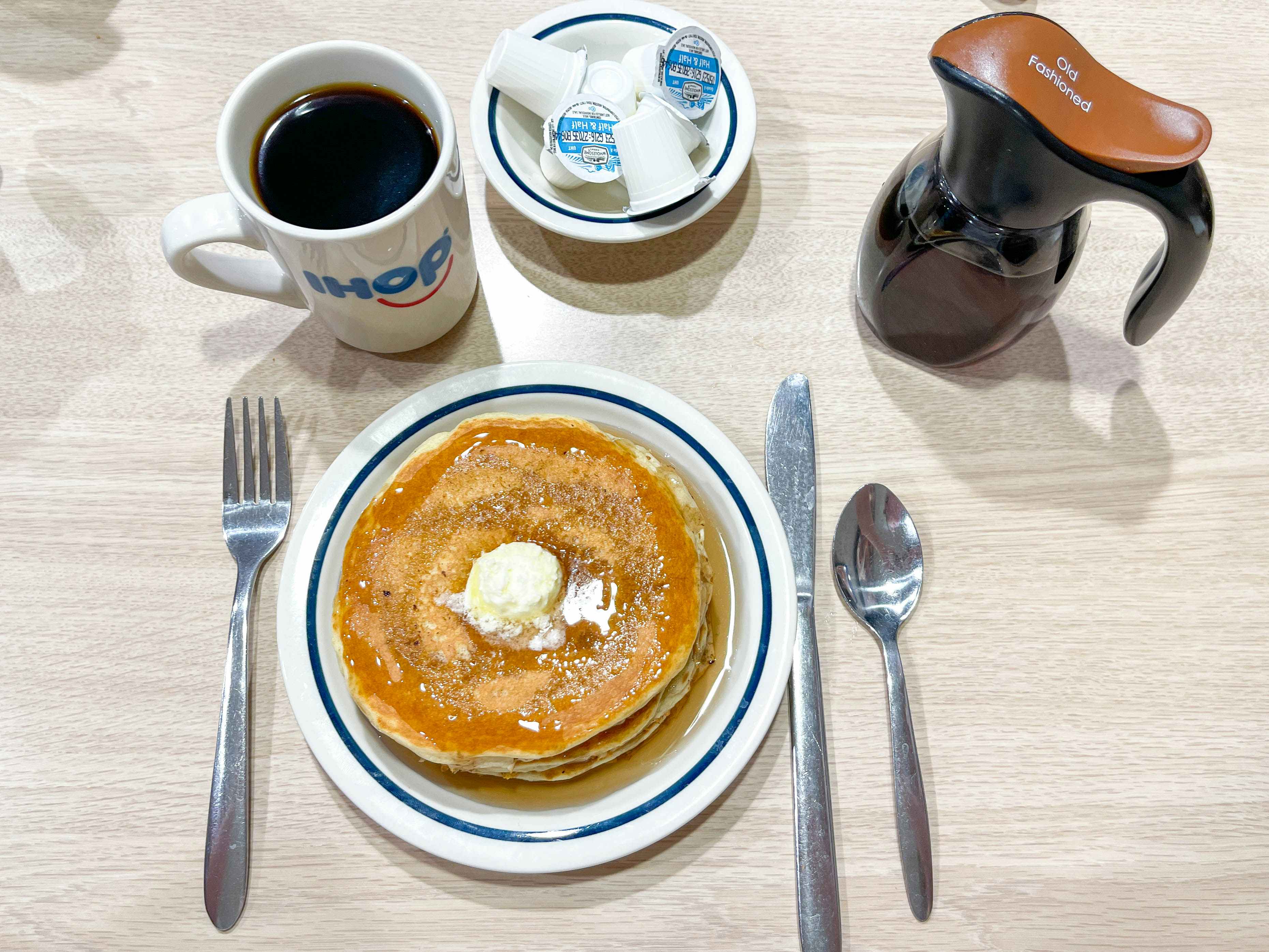 a plate with pancakes on a table with syrups