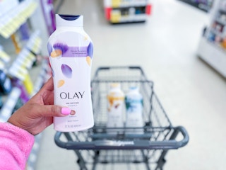 hand holding olay body wash in front sof shopping cart