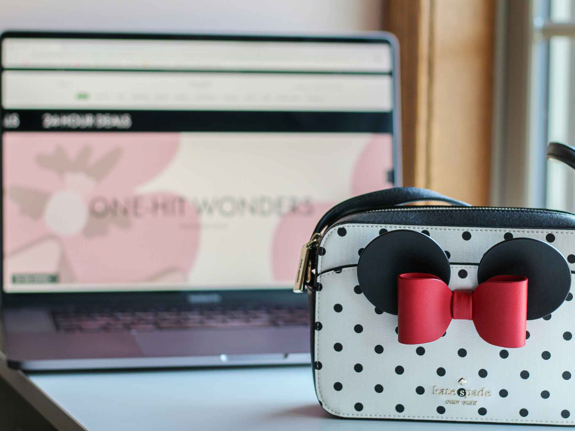 a kate spade purse sitting in front of a computer screen that has the kate spade website on it