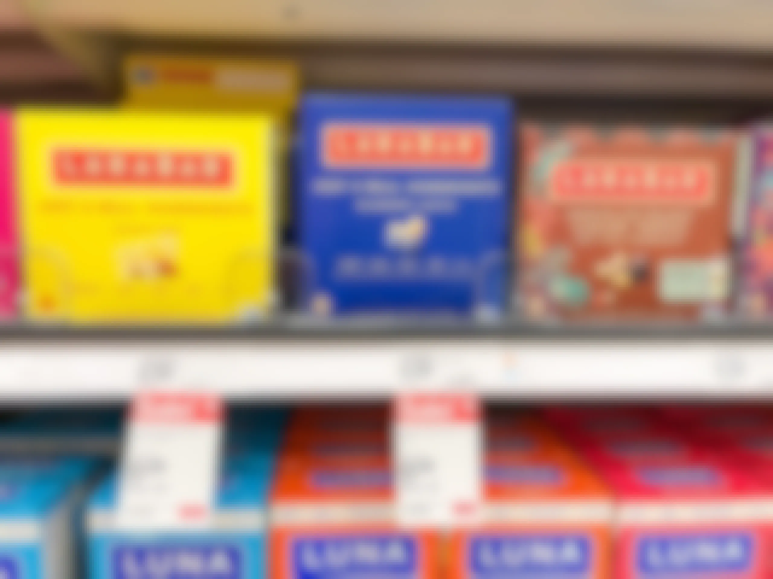 A variety of Larabar bars sitting on a store shelf with sale prices underneath them.