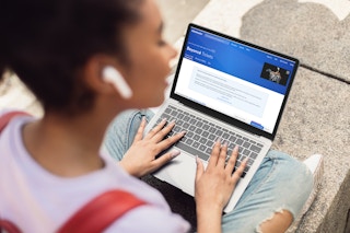 Young woman looking at the Beyonce tour sales page at Ticketmaster with earbuds in.