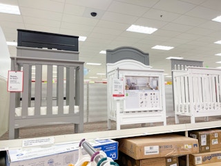 A variety of cribs sitting on a store shelf.
