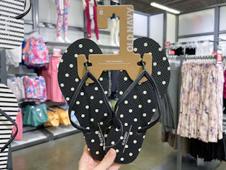 hand holding up a pair of polka dot flip flops