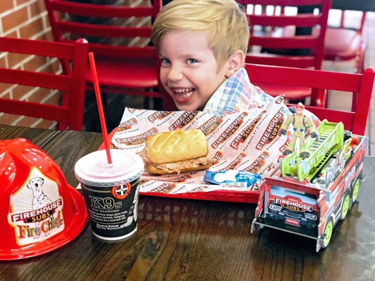 happy child eating a kids meal at firehouse subs restaurant