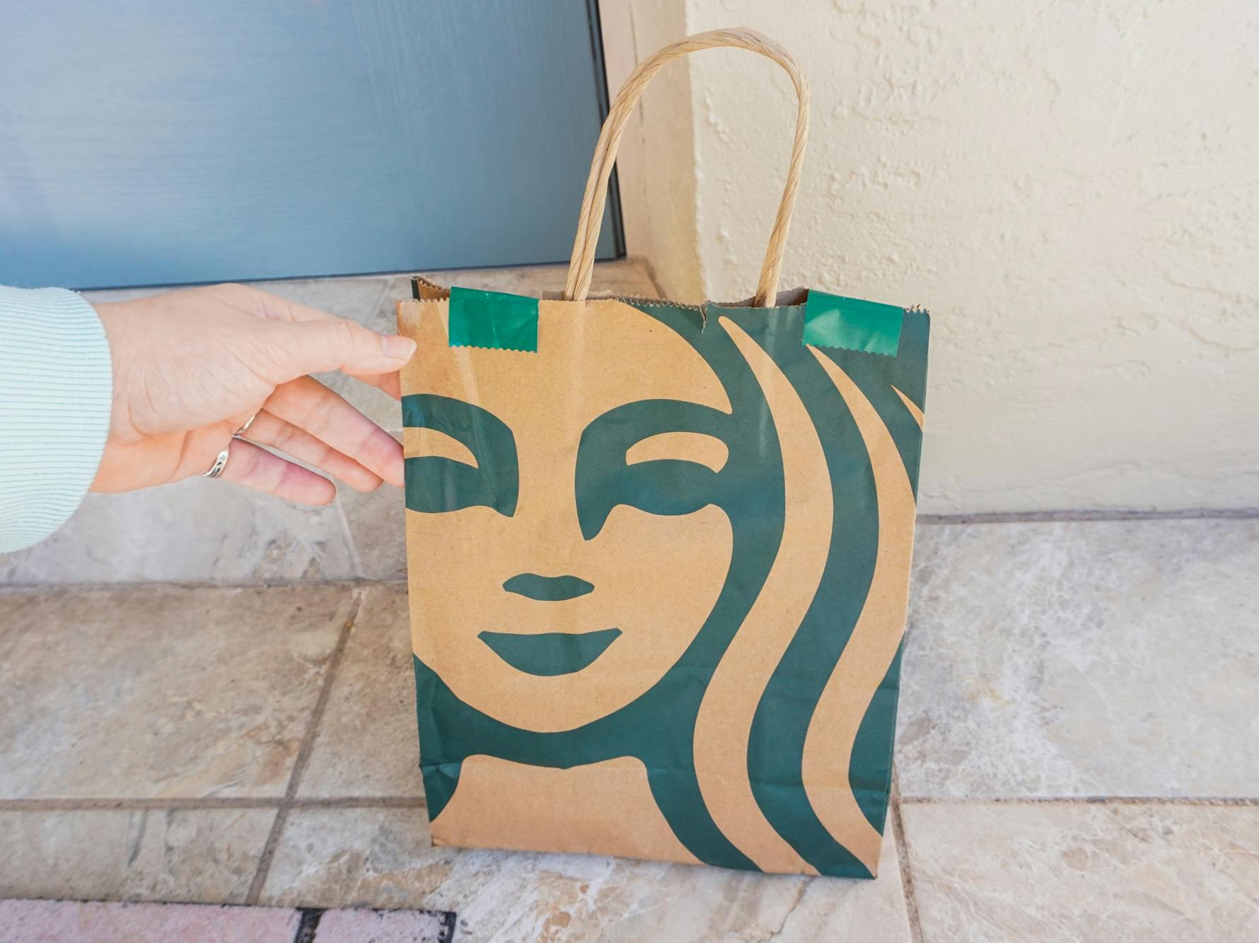 Someone picking up their Starbucks order that was dropped off at their front door