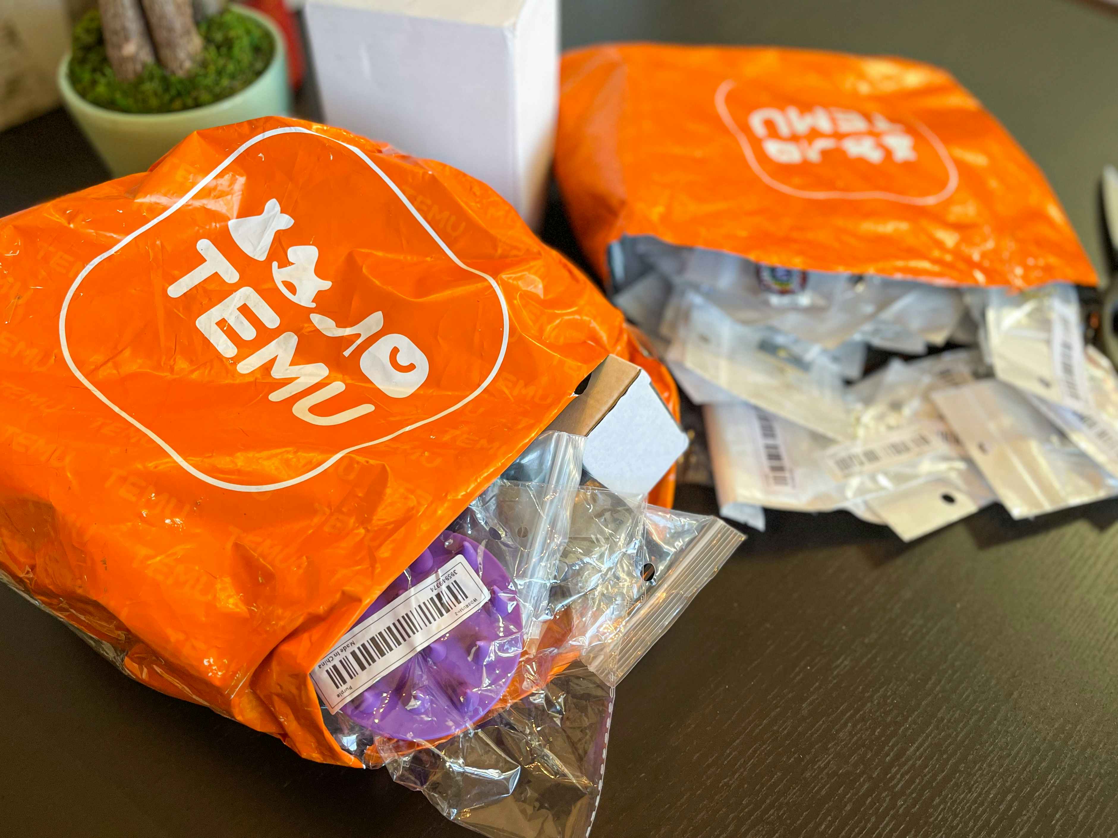 Two orange Temu shipping packages on a table opened with items spilling out