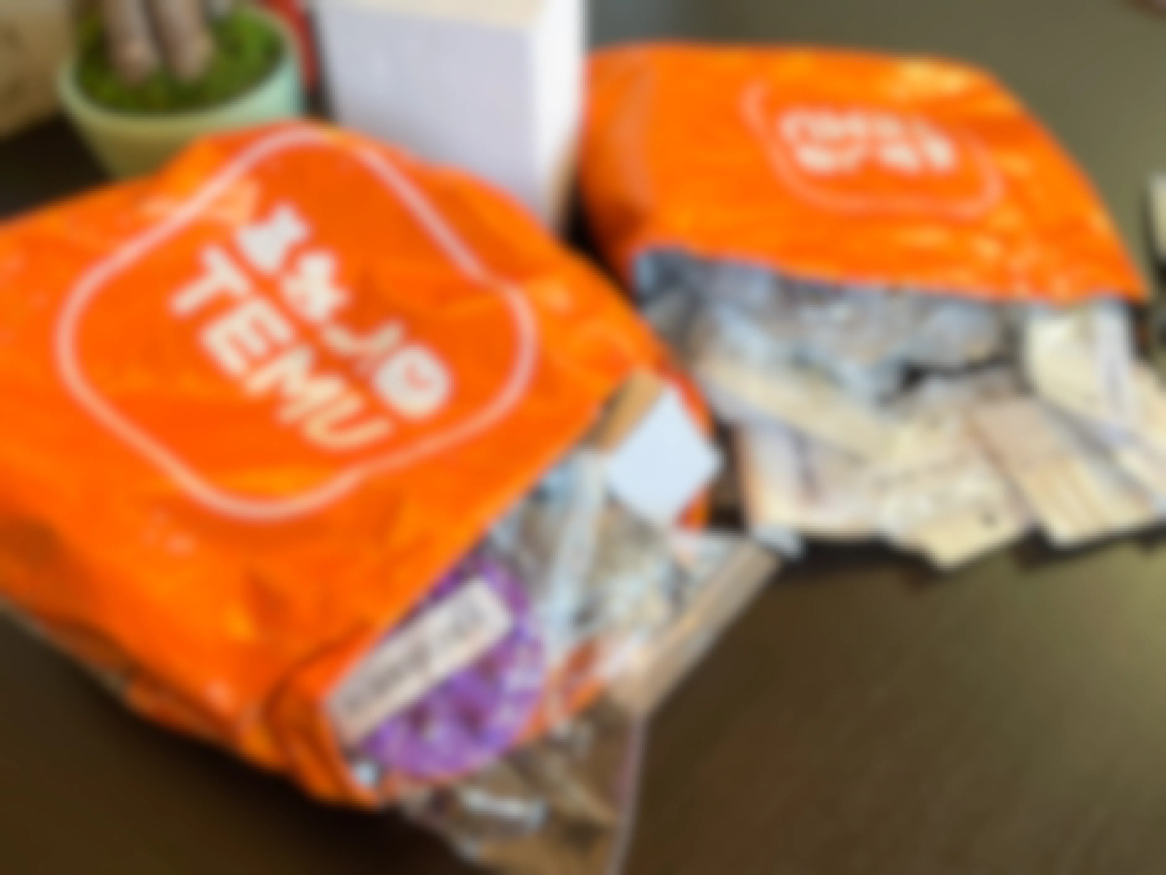 Two orange Temu shipping packages on a table opened with items spilling out