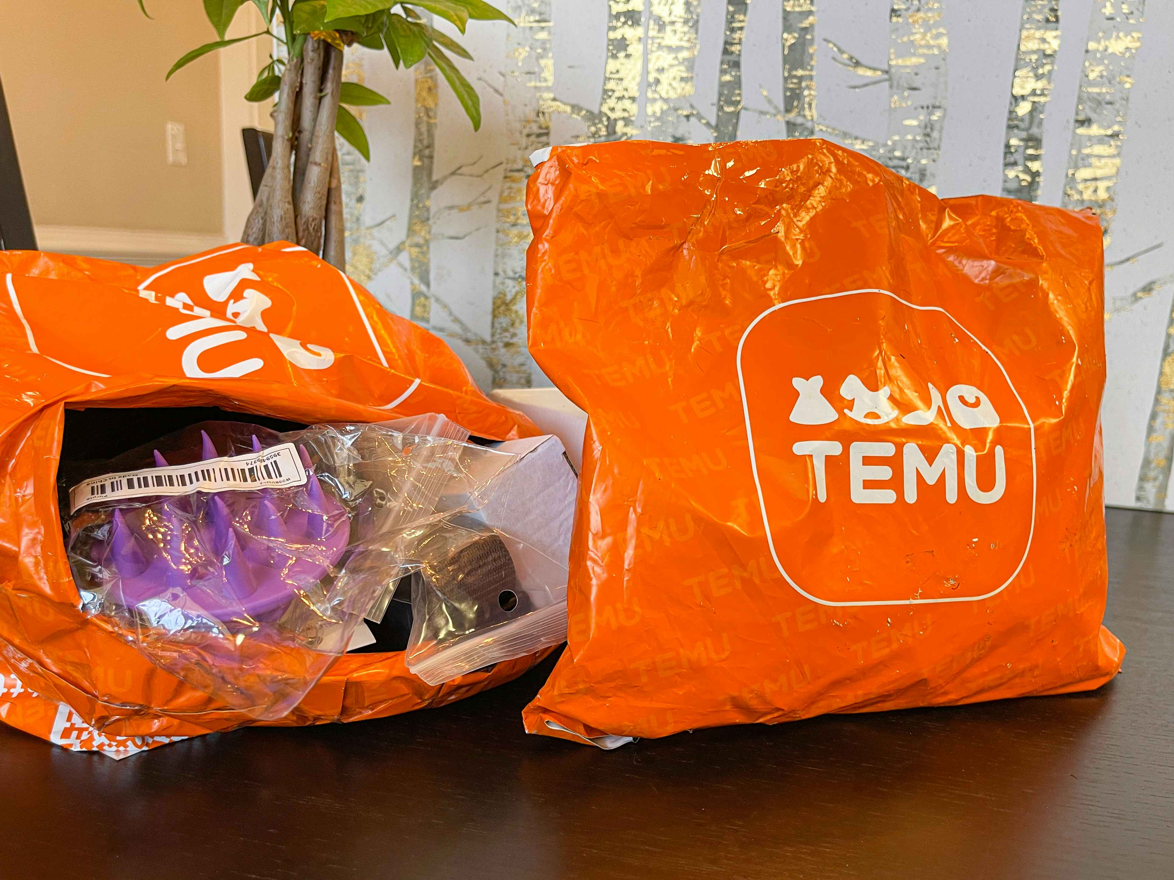 An orange Temu shipping package sitting upright on a table next to an opened Temu shipping package with items spilling out