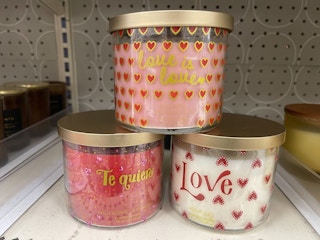 Three Valentine's Day candles sitting on a store shelf.
