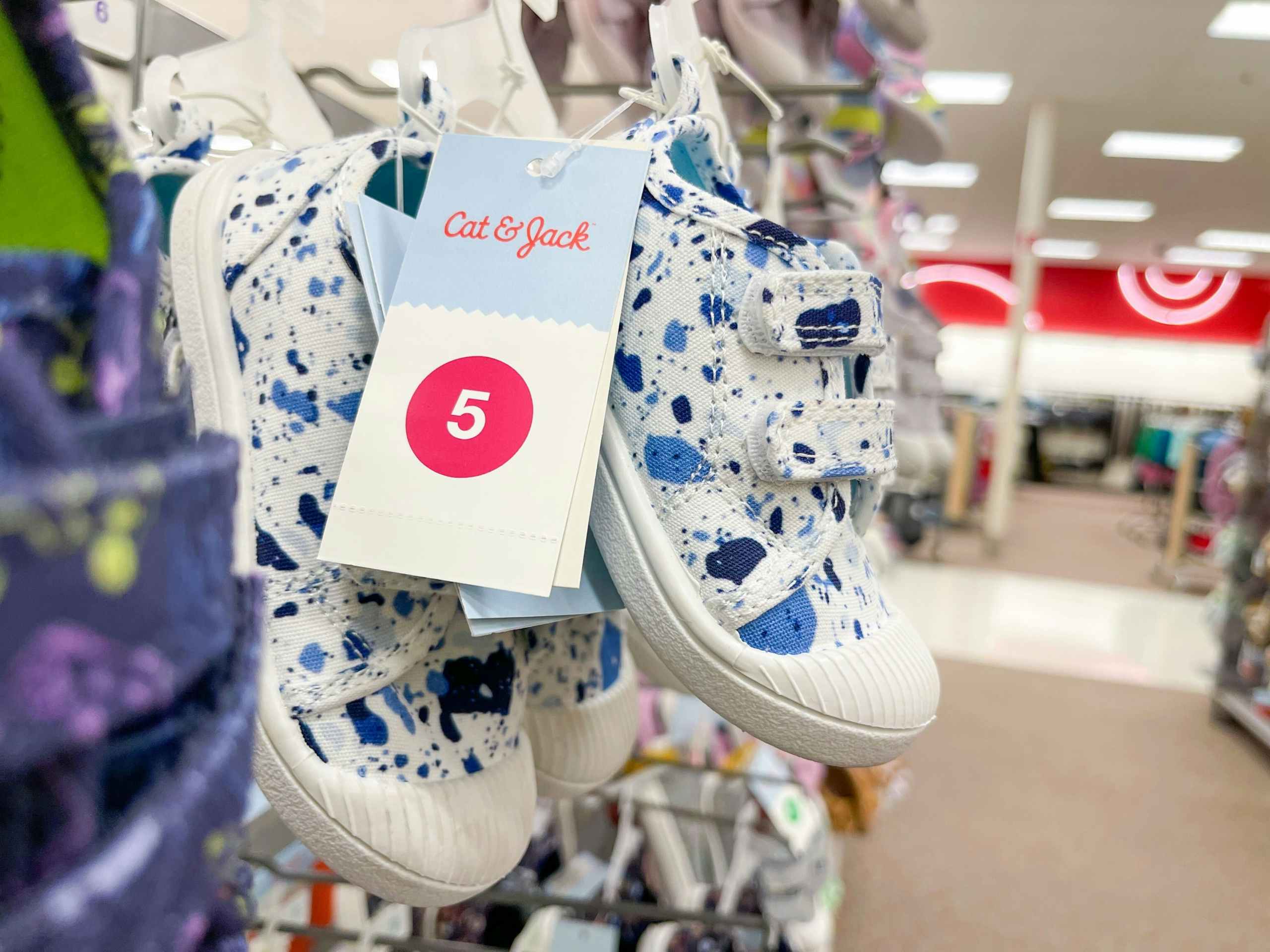 A closeup of a toddler's sneaker hanging from a store rack.