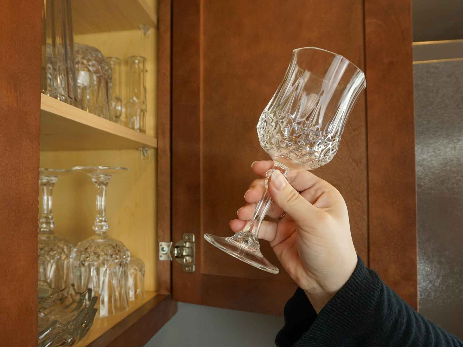 Someone putting glassware into their kitchen cupboard