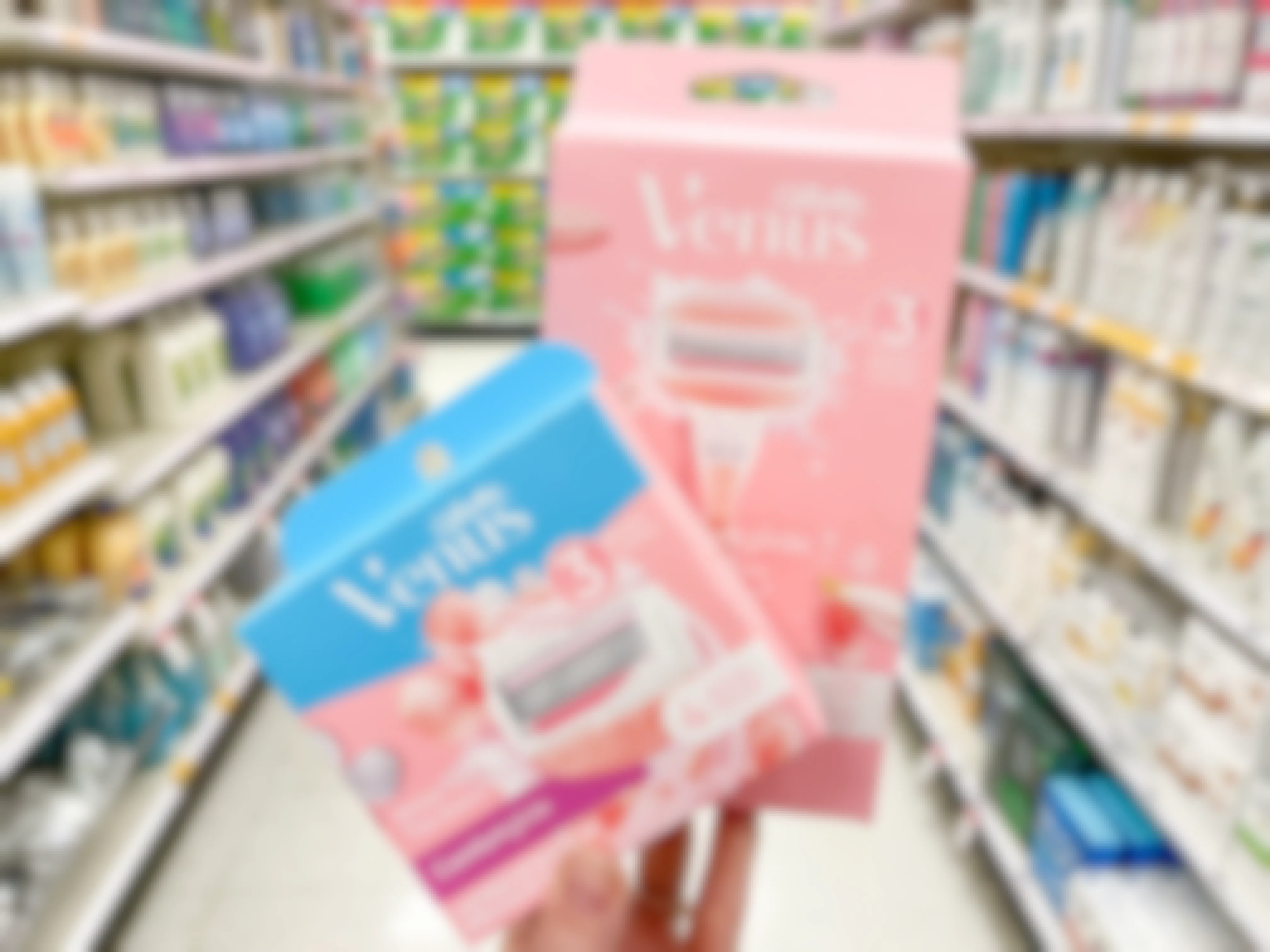 A Venus White Tea razor and a Venus refill pack held out by hand in front of a store aisle.