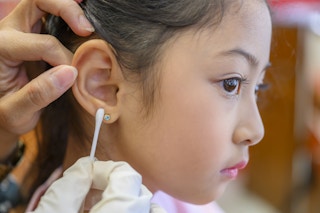 A little girl having her new piercing cleaned by the piercer