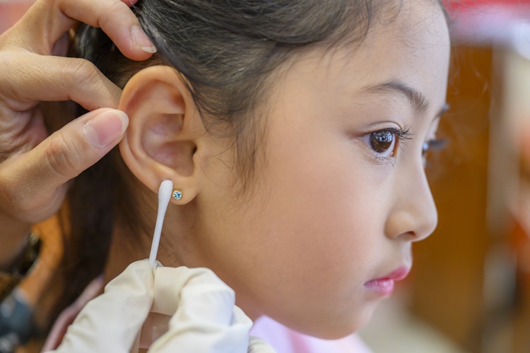 A little girl having her new piercing cleaned by the piercer