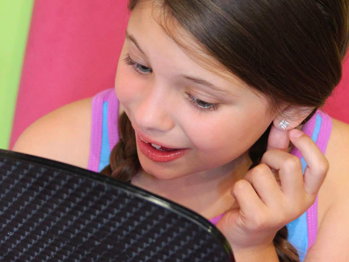A child looking at the new piercings in her ears from Sweet and Sassy kids spa