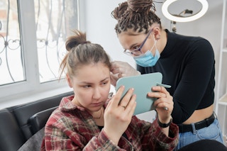 A teen having an ear piercing done at a professional shop