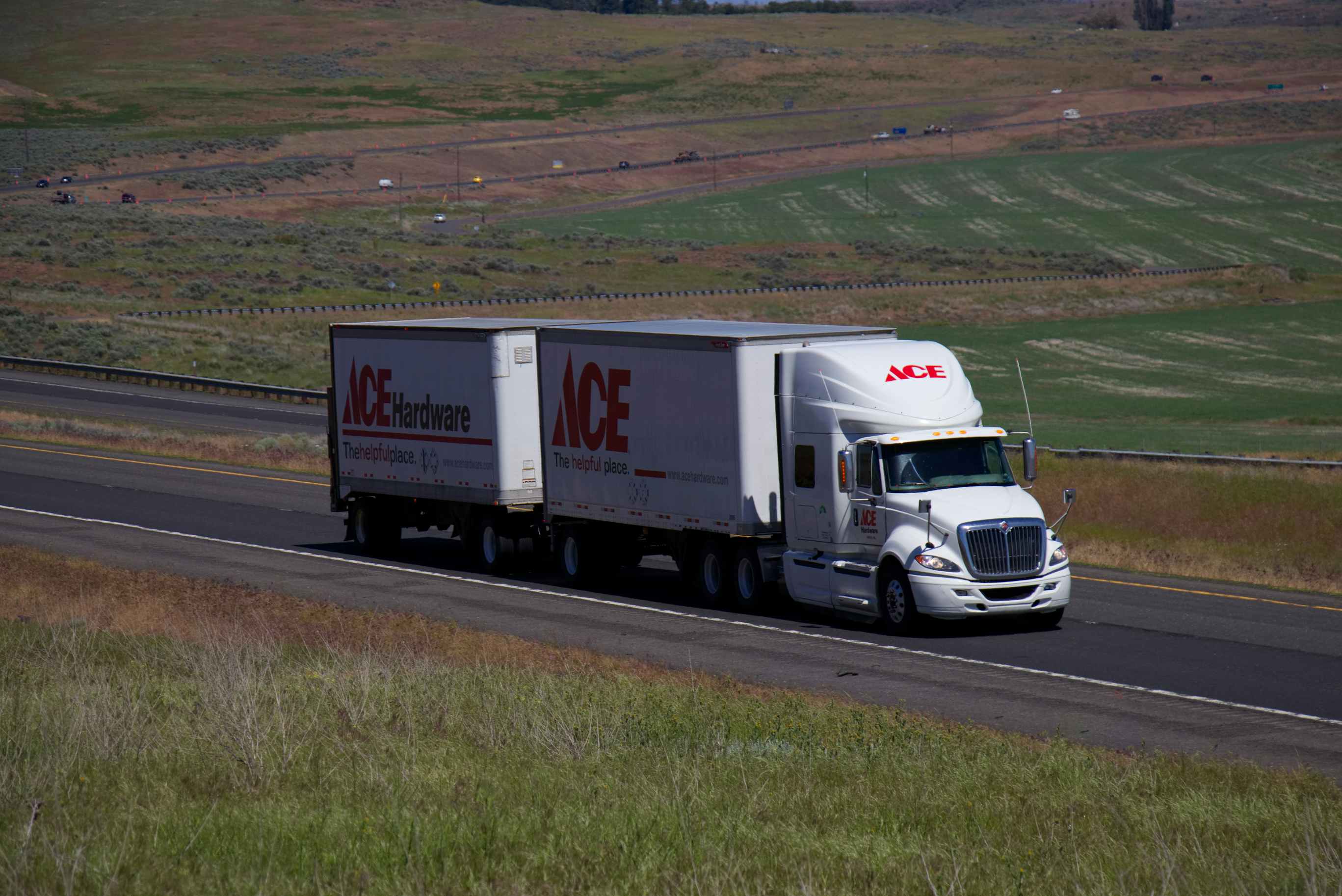 A large ace hardware truck driving down a road in a deserted area