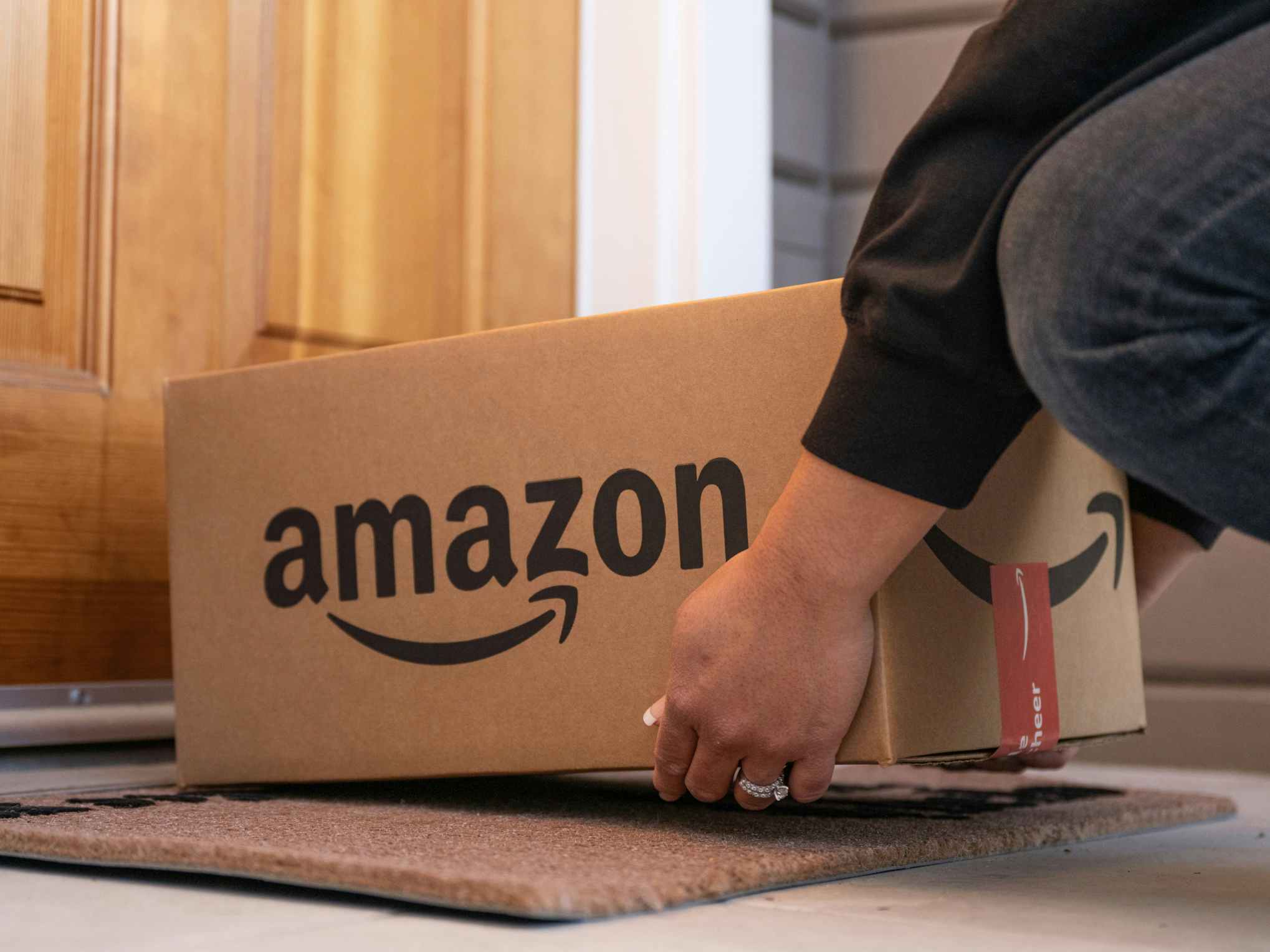 a person putting an amazon box on a front doorstep
