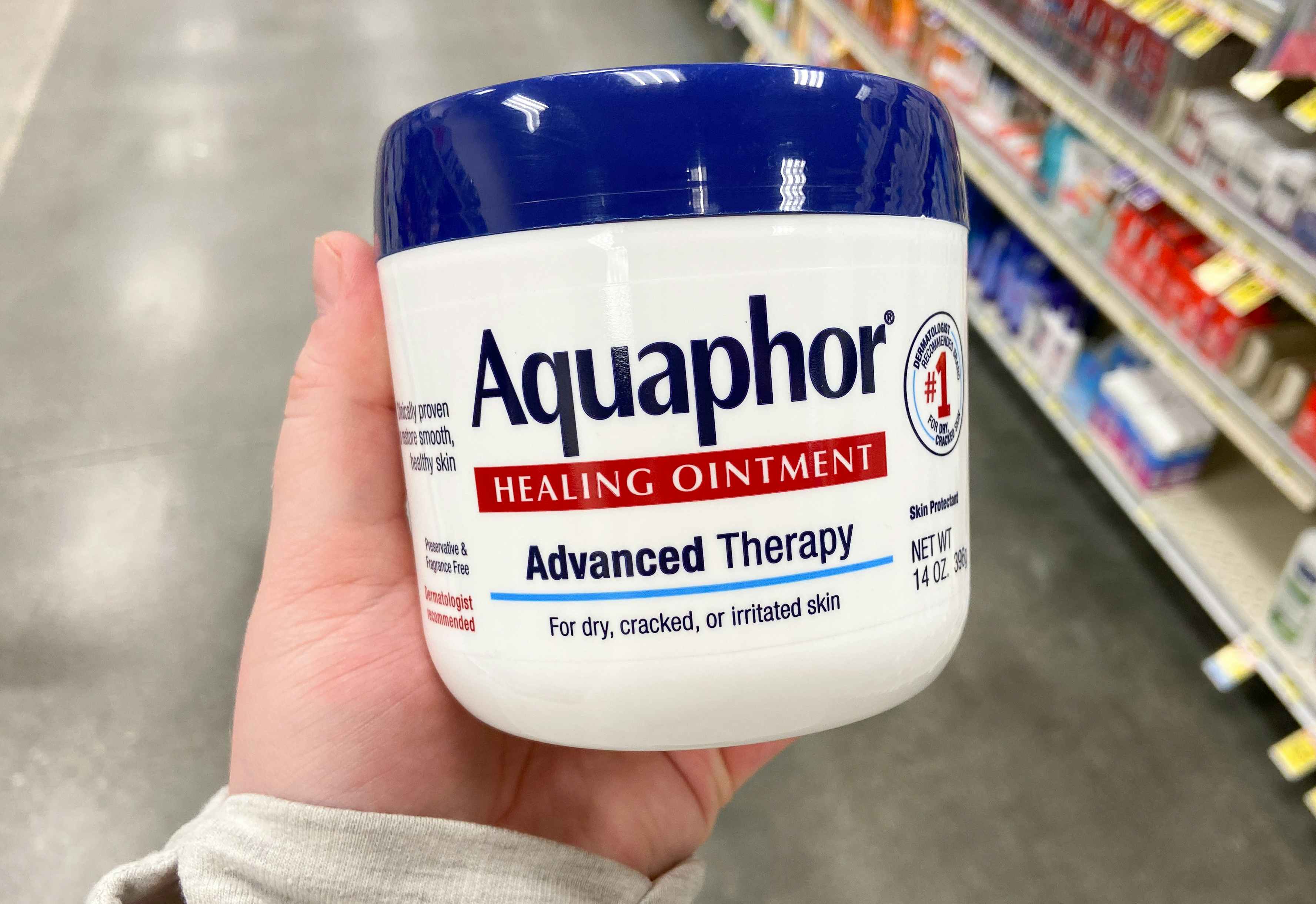 hand holding a jar of aquaphor healing ointment