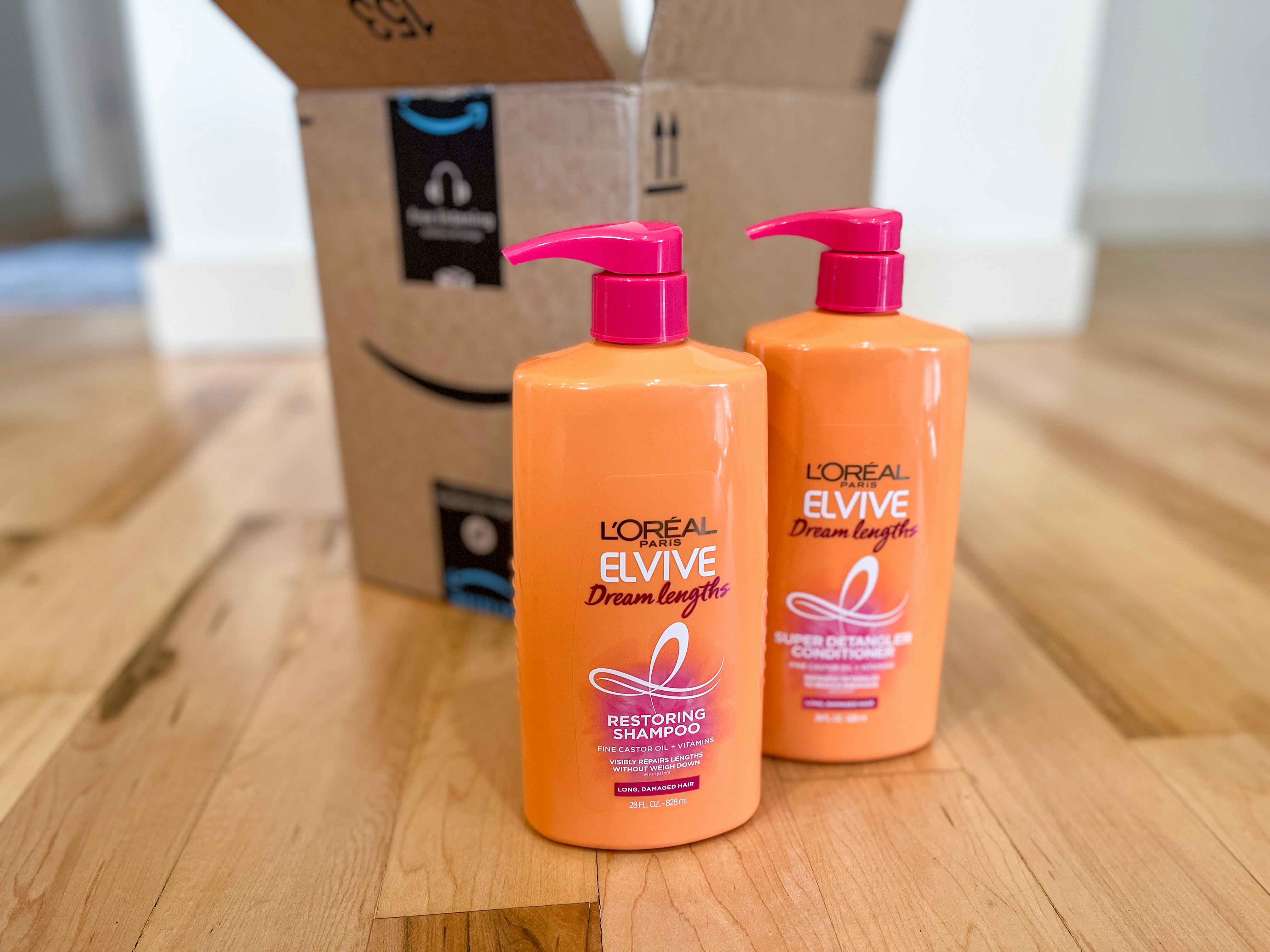 two bottles of loreal paris elvive shampoo and conditioner placed on the floor in front of an amazon prime box