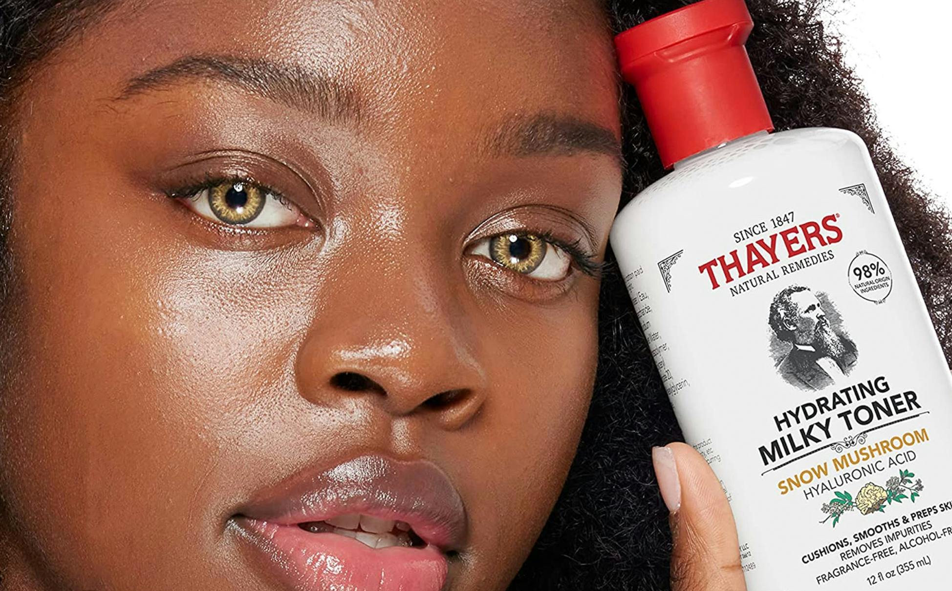 woman holding a bottle of thayers milk toner near her face