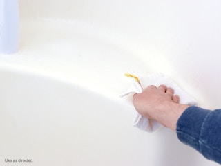person wiping bathtub ledge after spraying clorox bathroom ultra foamer spray