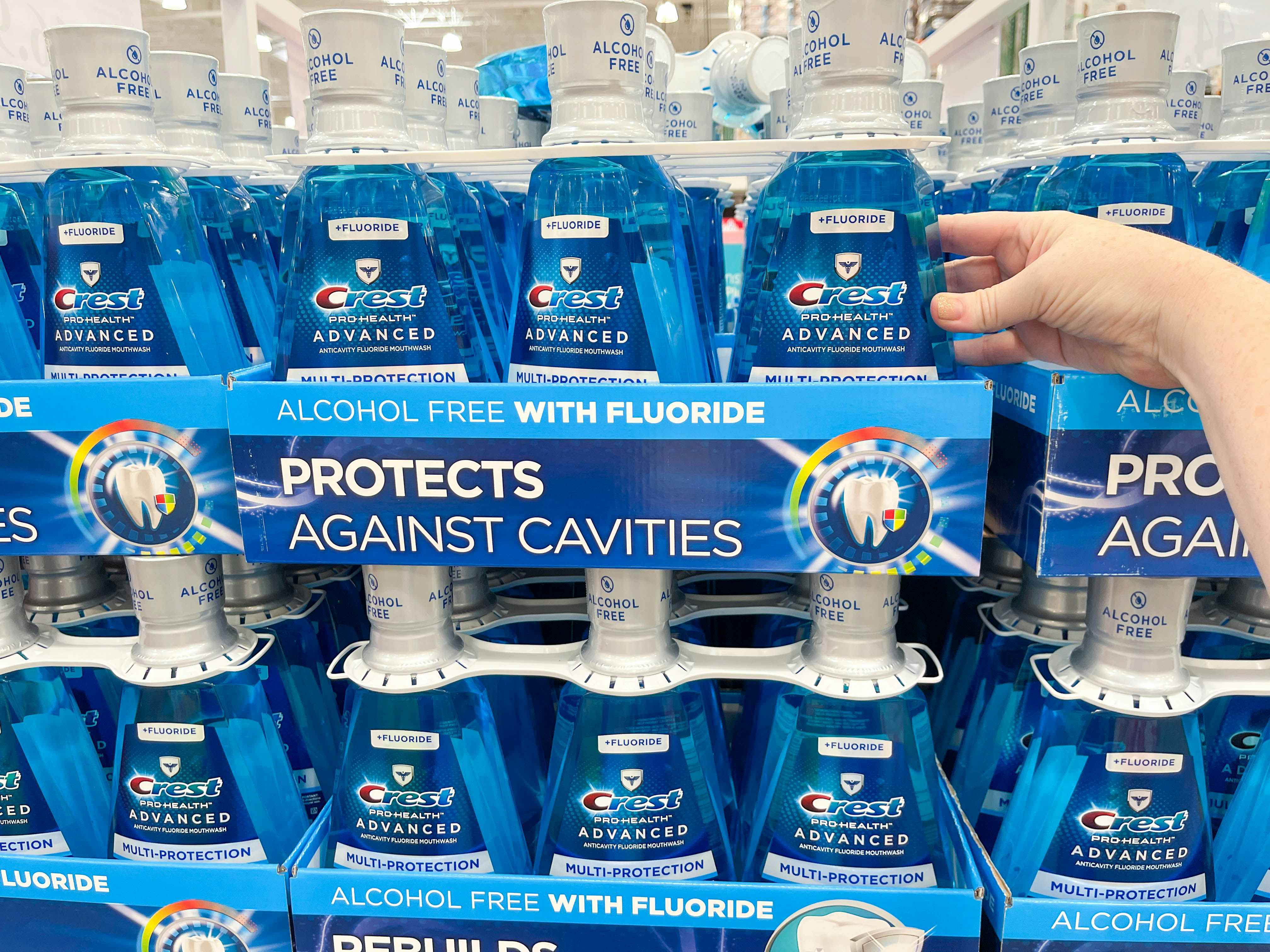 a person grabbing a bottle of crest moutwash in store