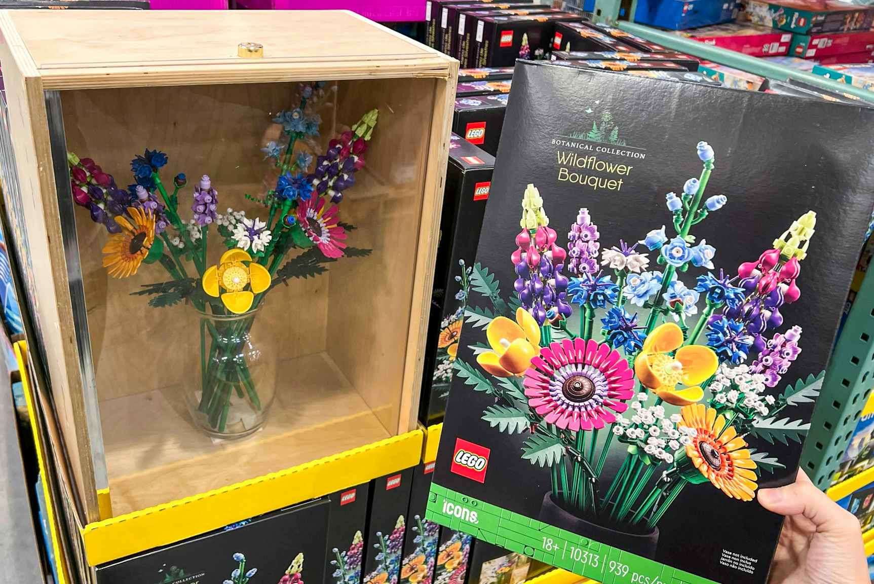 someone holding a box for Lego Wildflower Bouquet set next to a display