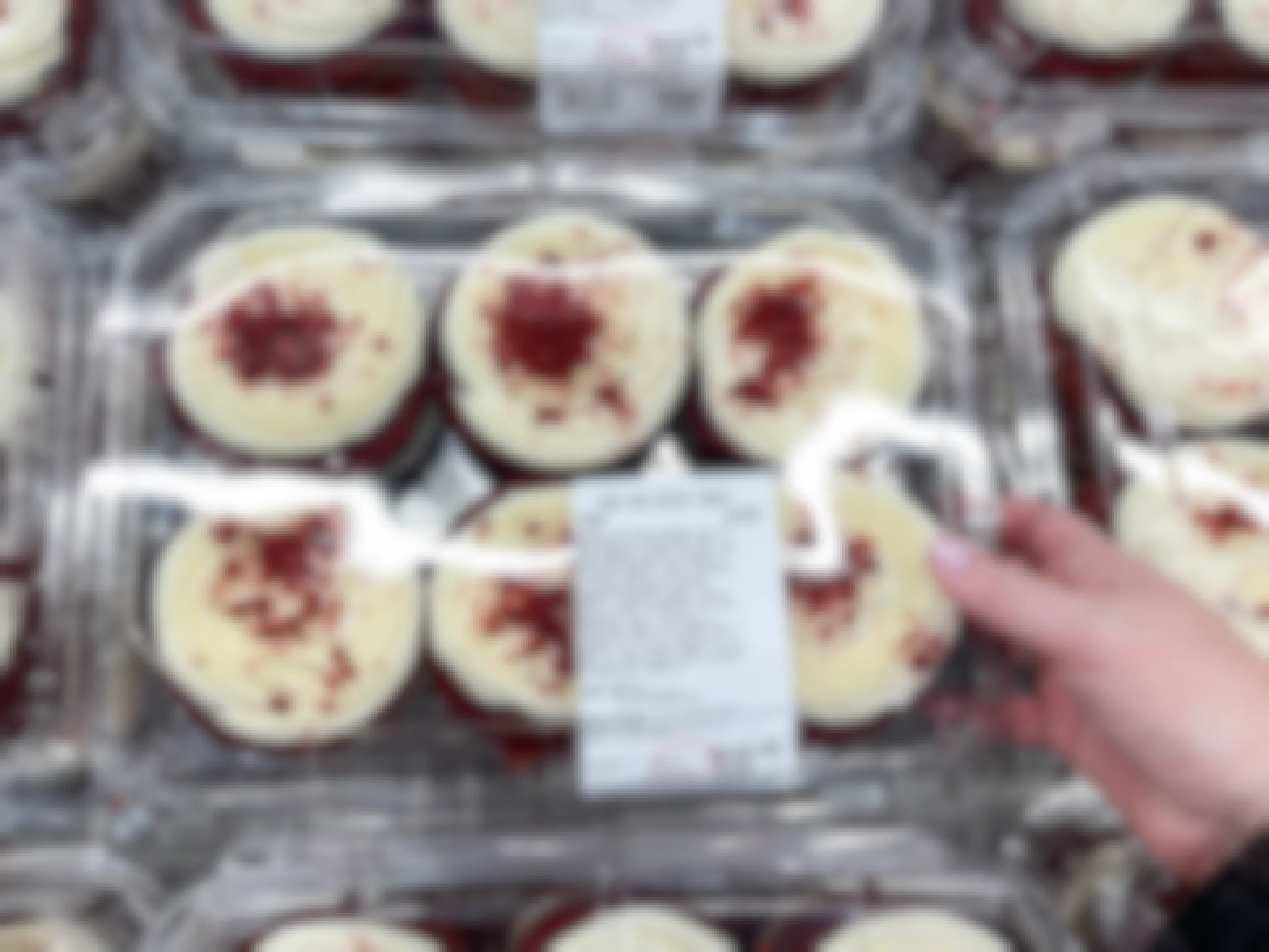 A person grabbing a package of red velvet min cake from dessert area in store 