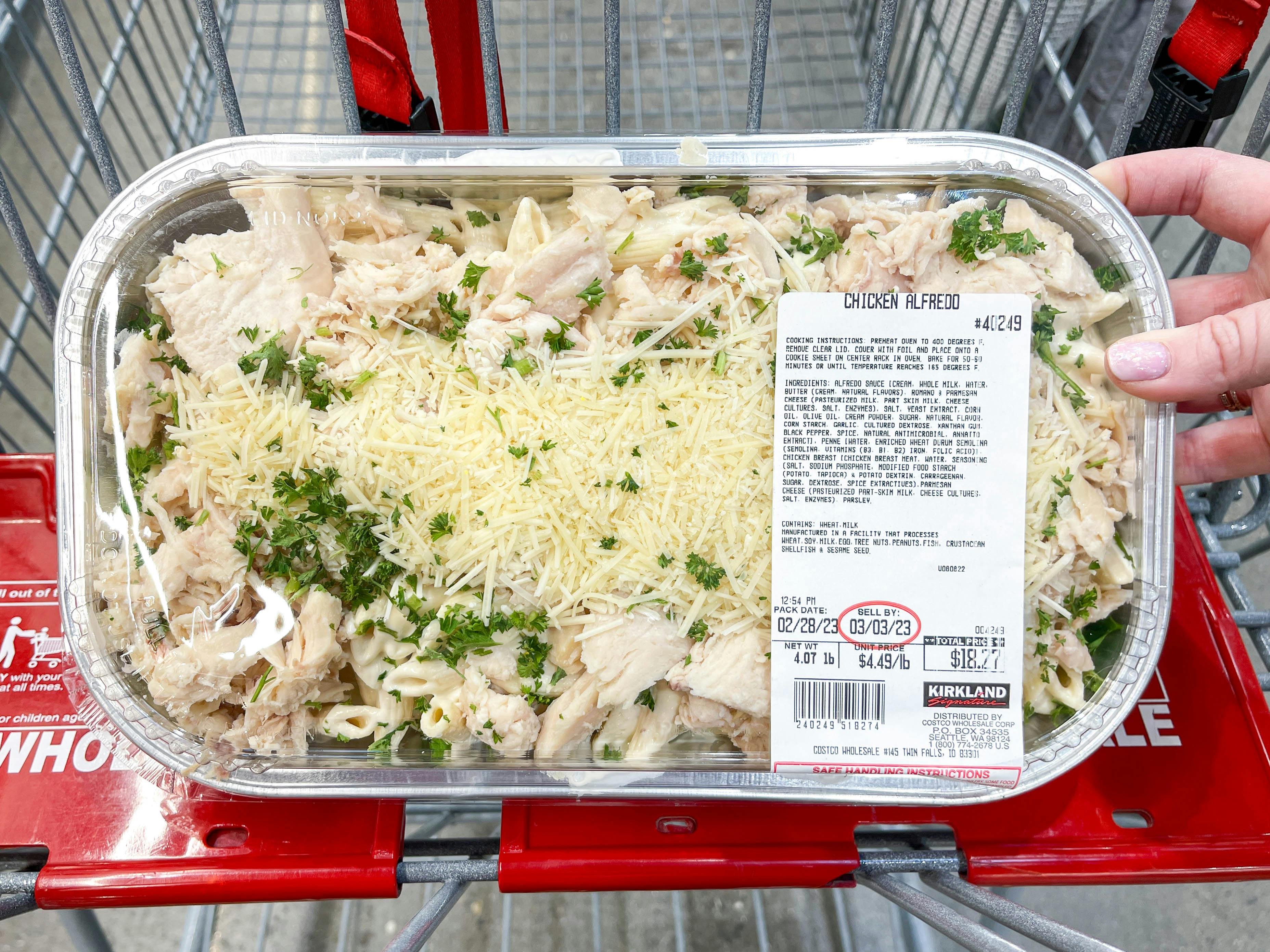 a person holding up a costco prepared meal in cart 