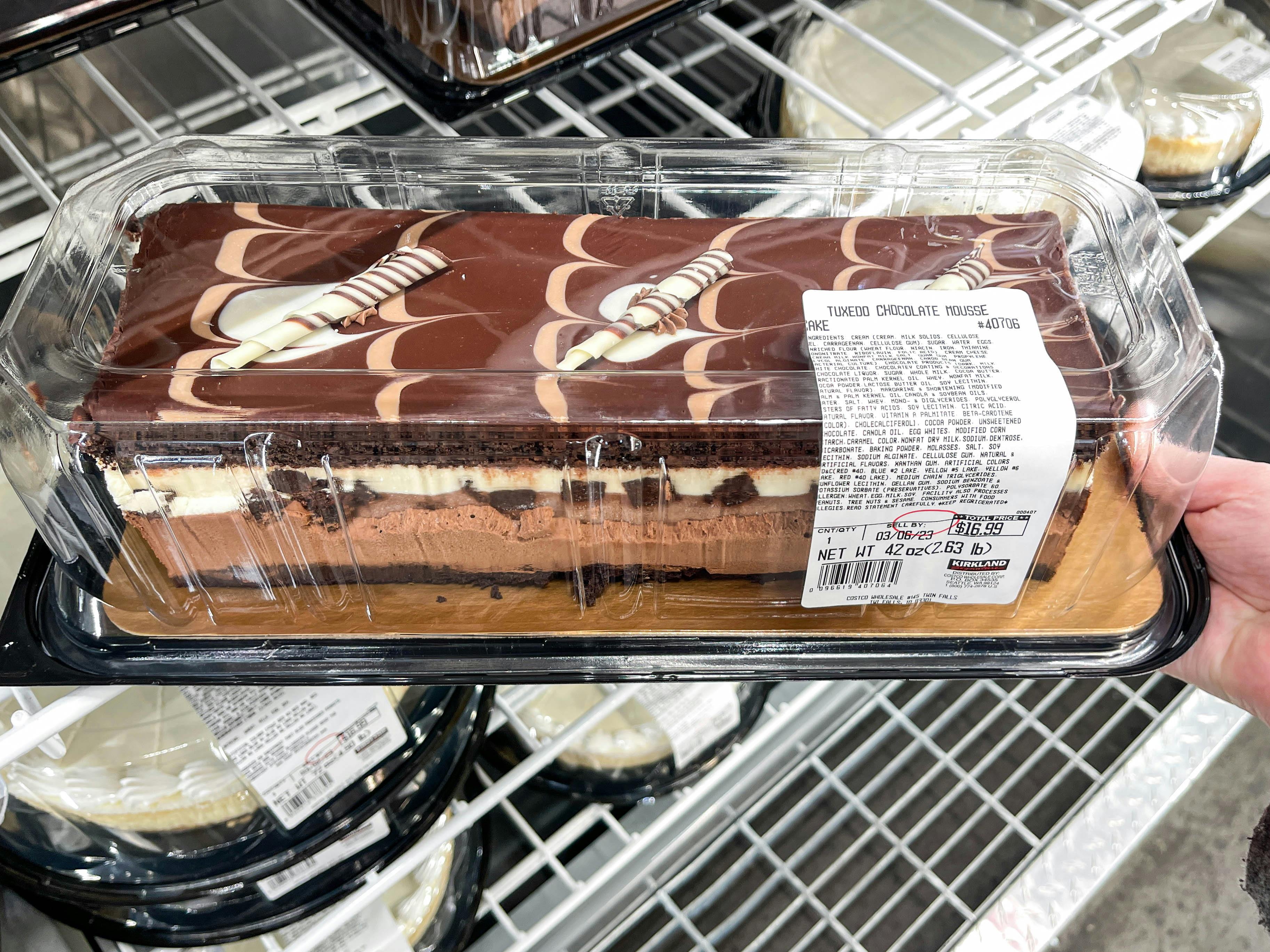 A person grabbing a tuxedo chocolate mousse from dessert area in store 