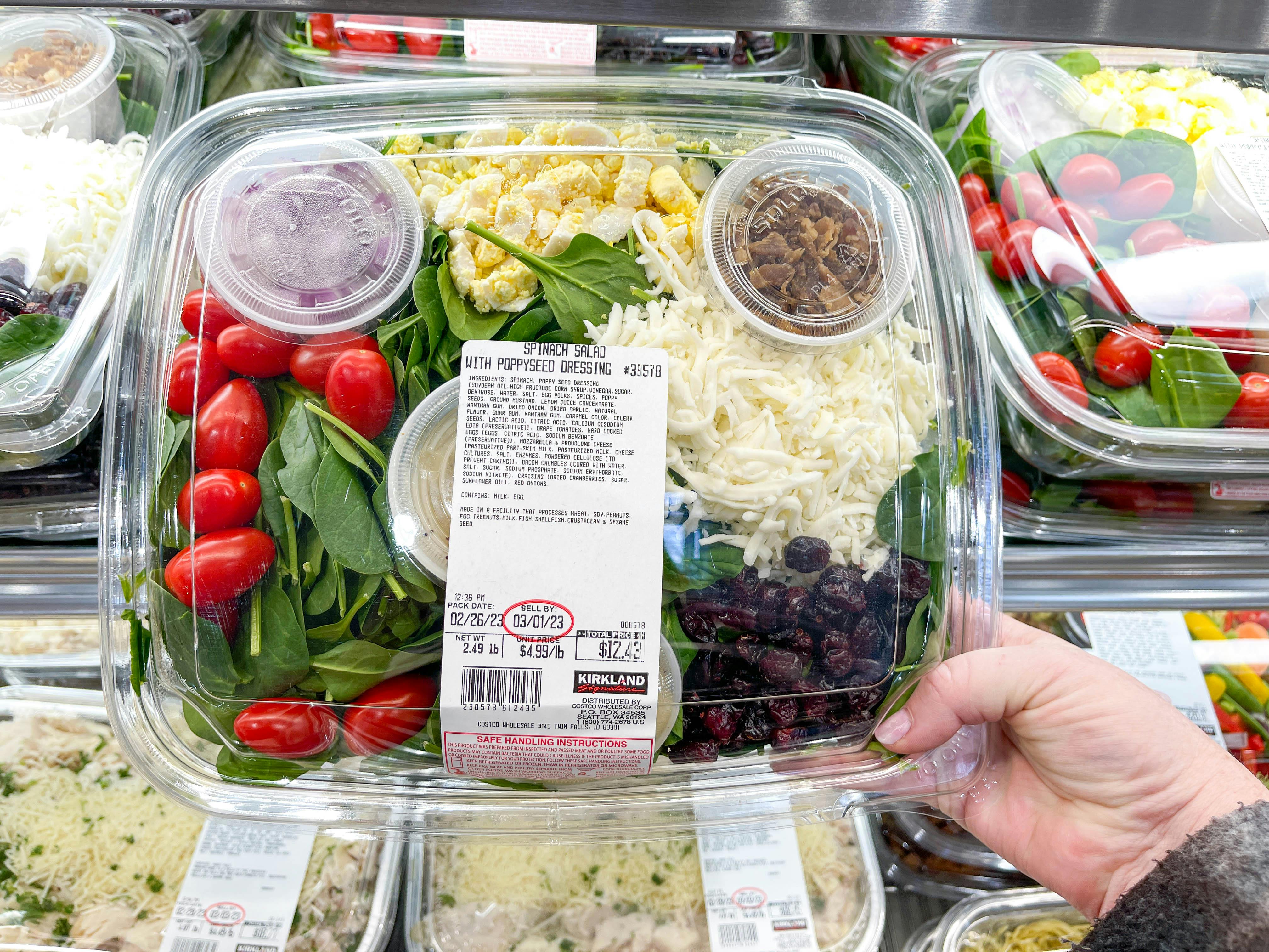 a person holding up a costco prepared salad kit in store 