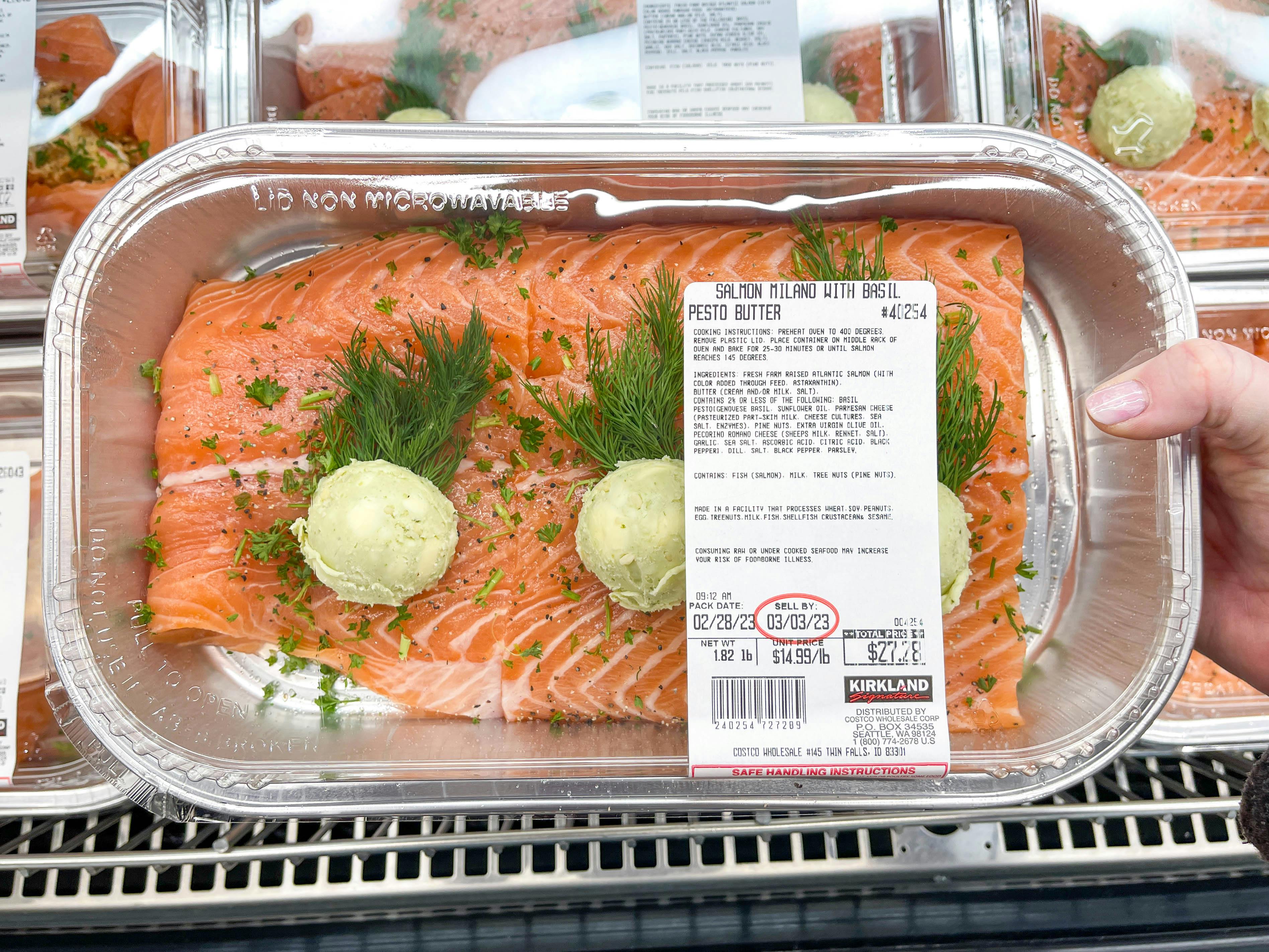 a person holding up a costco salmon meal in store 