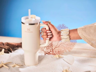 Hand holding a cream colored stanley cup