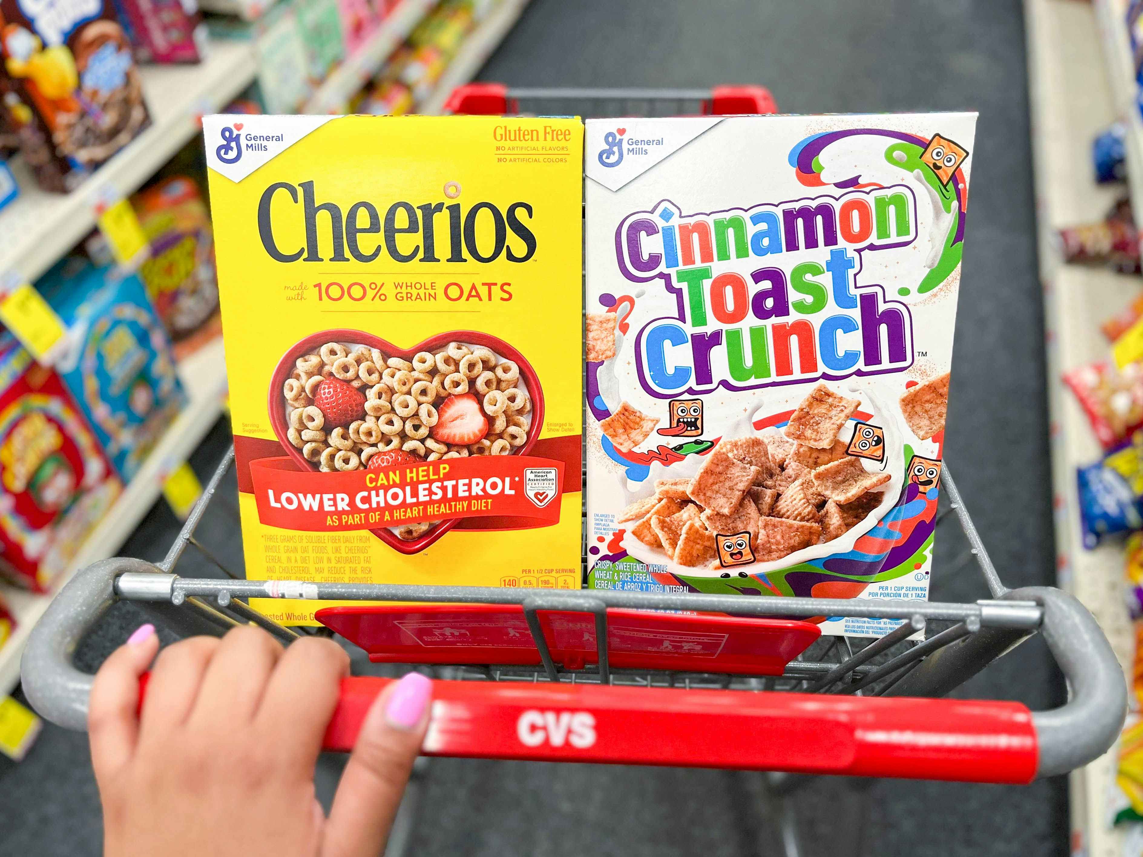hand pushing cart with a box of Cheerios and Cinnamon Toast Crunch inside