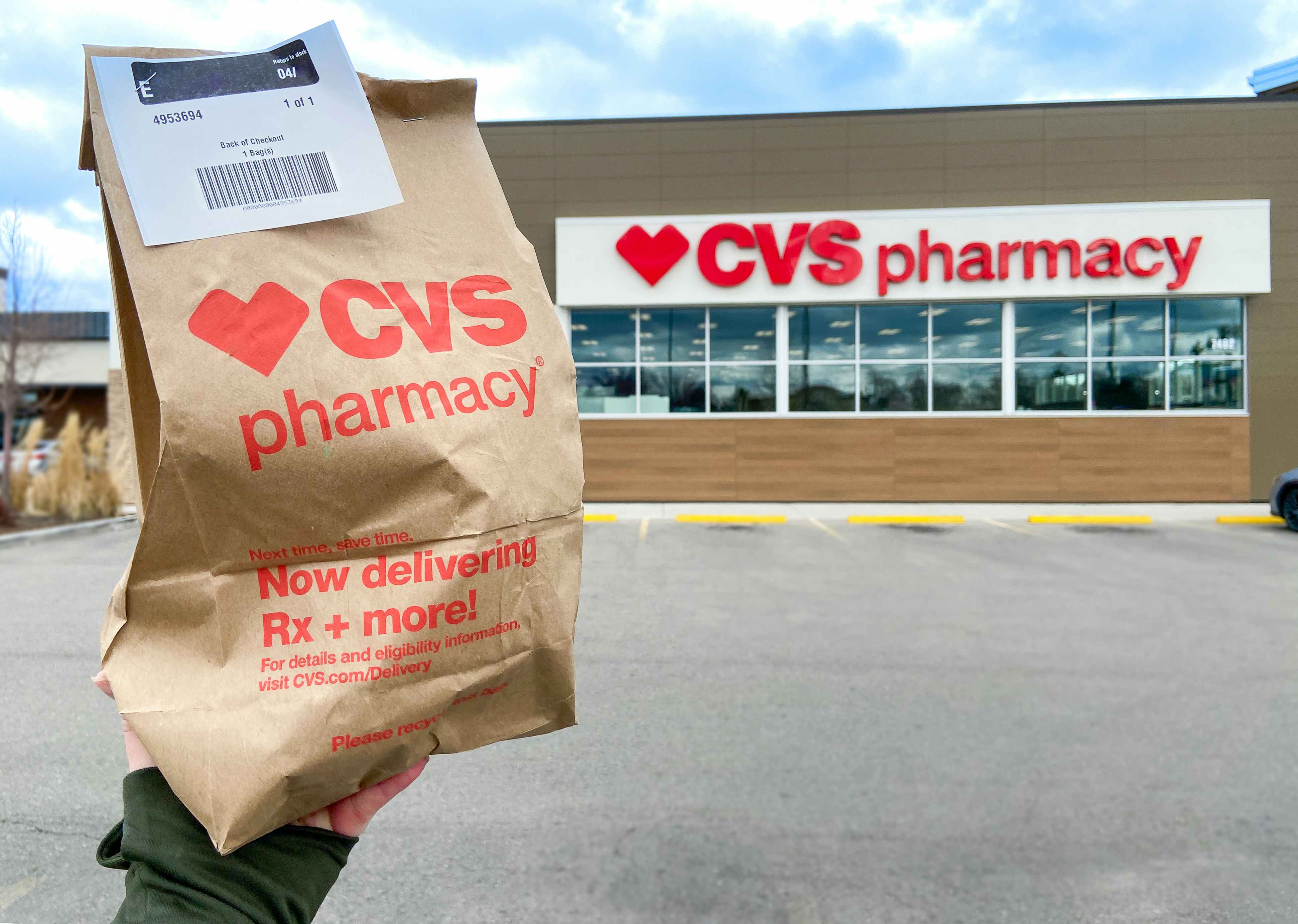 hand holding CVS Pharmacy store bag in front of storefront