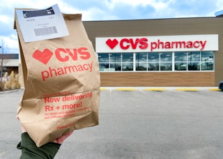 hand holding CVS Pharmacy store bag in front of storefront