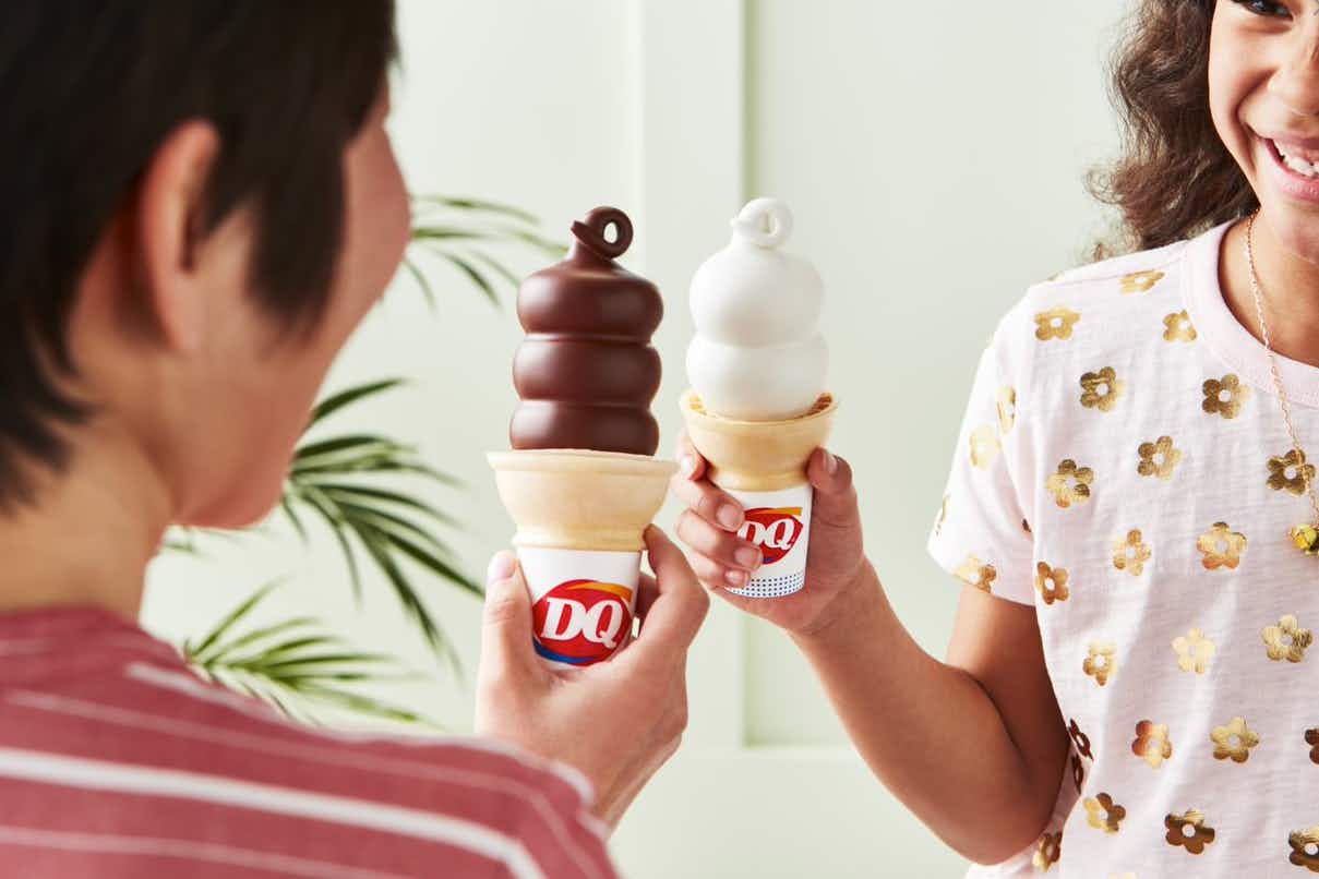 Two people. holding Dairy Queen cones, one regular and one dipped