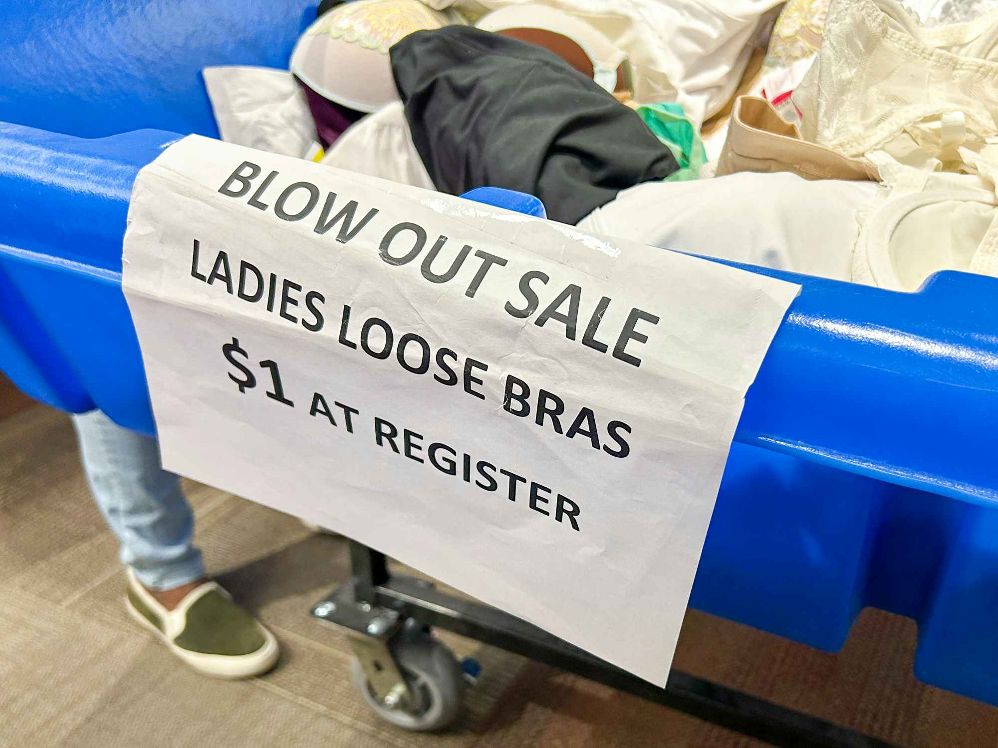 A bin with bras in it with a sign that says "Blow out sale. Loose bras $1 at register