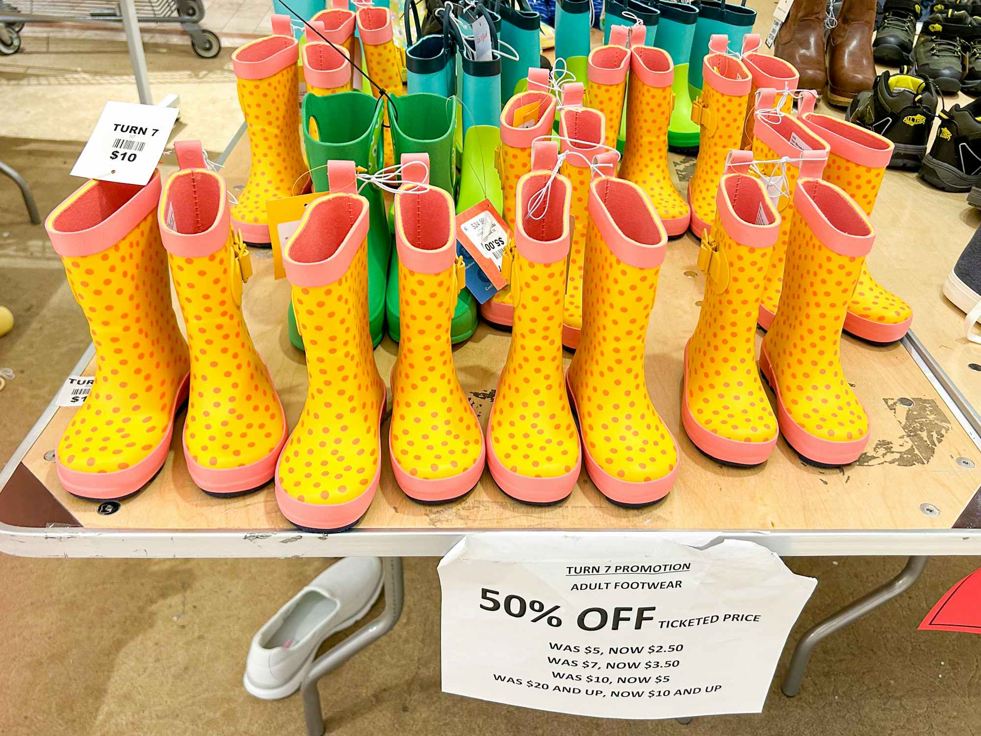 Some rain boots on a table with a 50% off sign