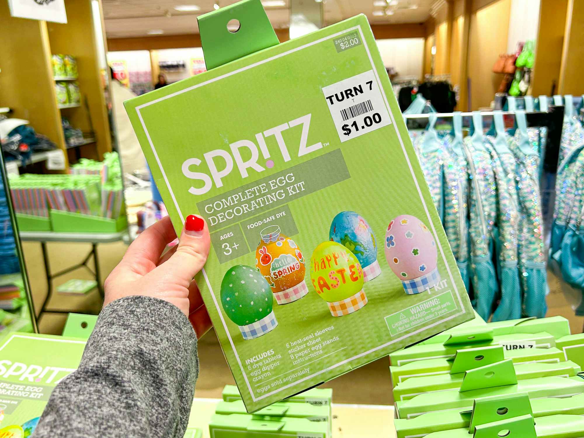 Someone holding a Spritz complete egg decorating kit inside a Turn7 store